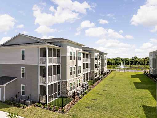 A large apartment complex with a green lawn in front at Verity Luxury Apartments, Florida 32960