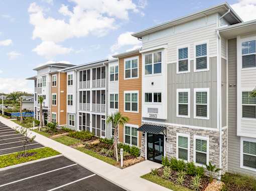 A row of modern apartment buildings with a parking lot in front at Verity Luxury Apartments, Florida