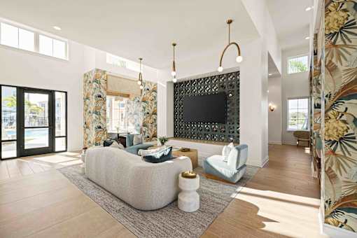 A living room with a white couch and a black TV mounted on the wall at Verity Luxury Apartments, Vero Beach, FL