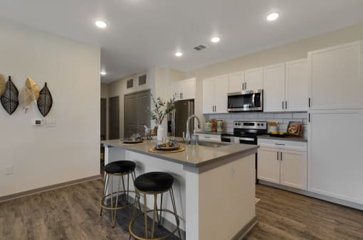 a kitchen with white cabinets and a large island with two stools  at Upland Flats, Colorado Springs, CO