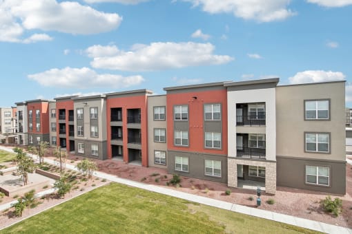 an apartment building with a green lawn and a blue sky at The Maddox Luxury Apartment Homes, Buckeye  