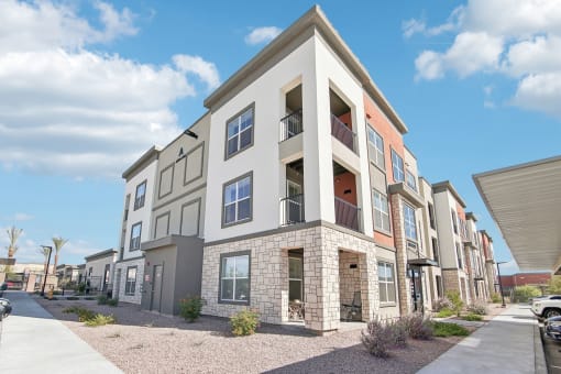 an apartment building with a sidewalk in front of it at The Maddox Luxury Apartment Homes, Buckeye Arizona  