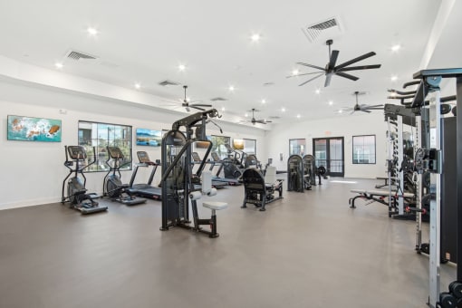 a gym with weights and cardio equipment in a building with white walls at The Maddox Luxury Apartment Homes, Buckeye Arizona  