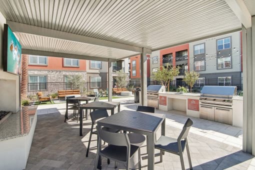 a patio with tables and chairs and a grill at The Maddox Luxury Apartment Homes, Buckeye Arizona  