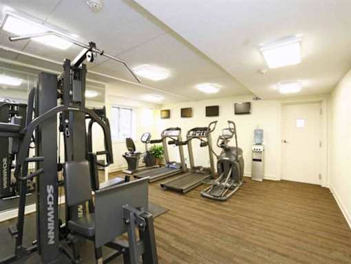 A gym with a variety of equipment including a squat rack, treadmill, and stationary bike.