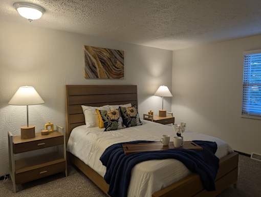 A bedroom with a bed, nightstands, and lamps.