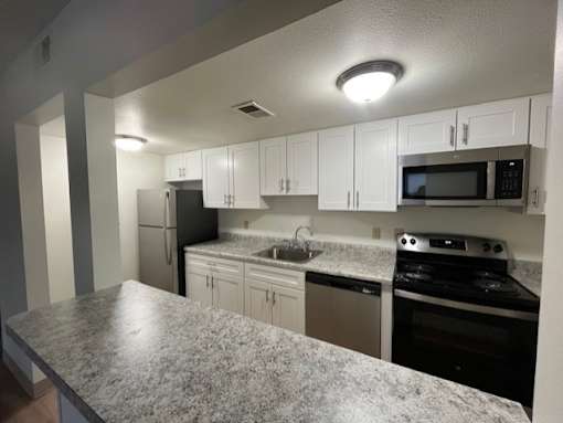 A kitchen with granite countertops and white cabinets.