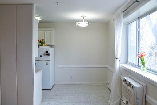 Dining space adjacent to kitchen with white cabinetry and bright window at 359 Edison.