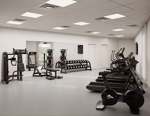 A gym with a variety of equipment including treadmills, weights, and exercise machines.