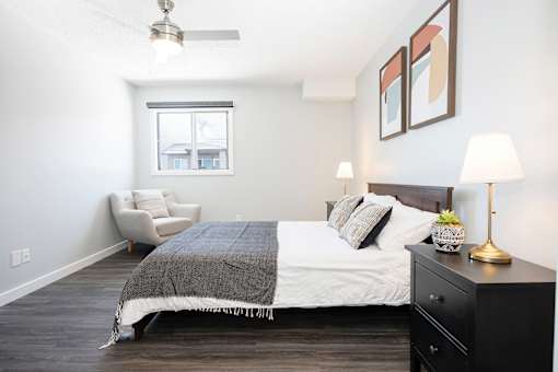 a bedroom with a bed and a chair and a window
