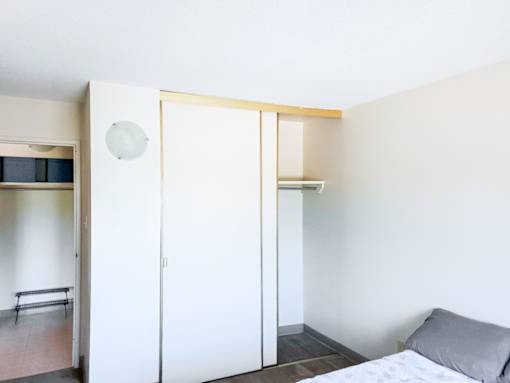 A spacious bedroom closet with sliding doors and a view into the hallway at 1025 Munroe Apartments.
