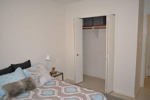View of bedroom with open closet and cozy bed setup at 359 Edison Apartments.