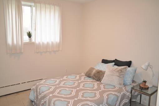 Furnished bedroom with double bed, side table, and large window at 359 Edison.