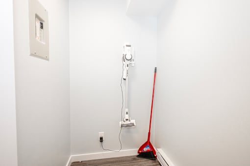 a white room with a red broom and a vacuum cleaner