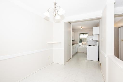 A white kitchen with a chandelier and a dining area.