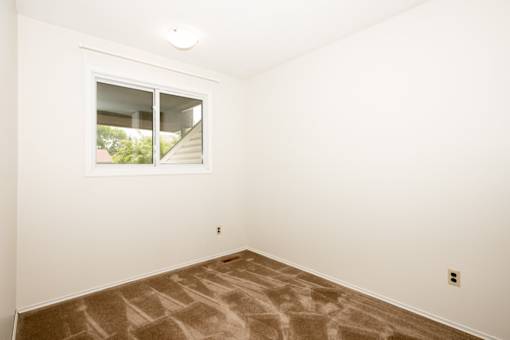 A room with a window and carpeted floor.