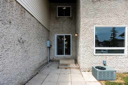 A house with a grey wall and a window showing a tree.