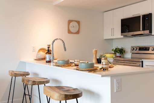 A kitchen with a white countertop and a wooden stool.