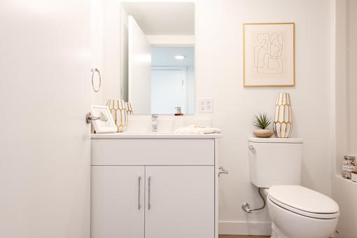 A white bathroom with a toilet, sink, and mirror.