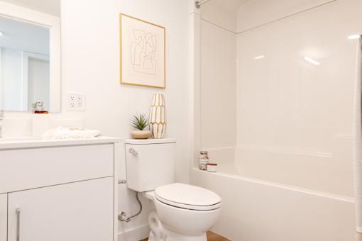A white bathroom with a toilet, sink, and a picture on the wall.