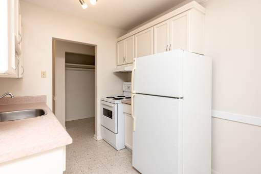 A white refrigerator is in a kitchen with a sink and stove.