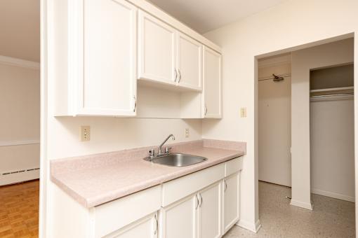 A kitchen with white cabinets and a pink countertop.