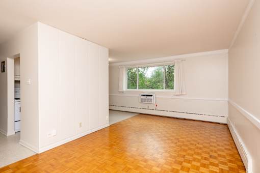 A room with a window and a wooden floor.