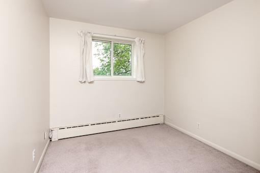 A room with a window and a white wall.