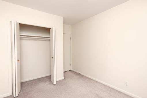 A room with a white door and carpeted floor.