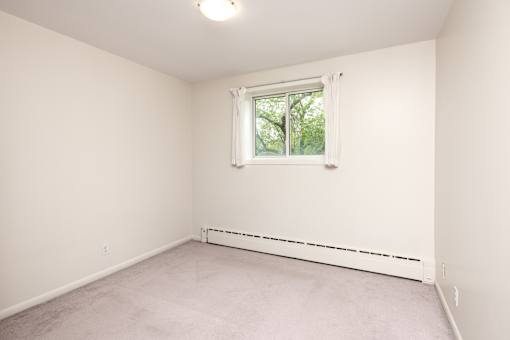 A room with a window and a white wall.