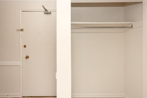 A white door with a gold handle and a white wall with a white shelf.