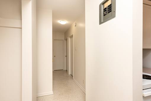 A hallway with a door on the left and a microwave on the right.