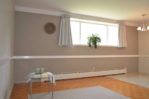 Living and dining area with large window, natural light, and neutral walls at 359 Edison Apartments.