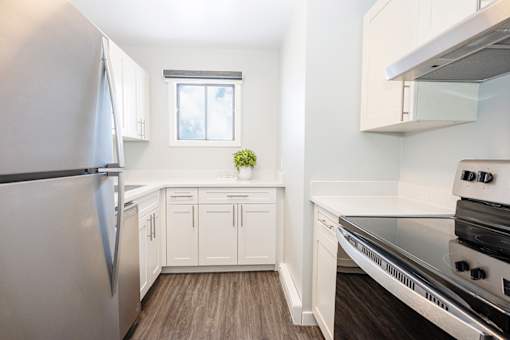 a white kitchen with stainless steel appliances and white cabinets