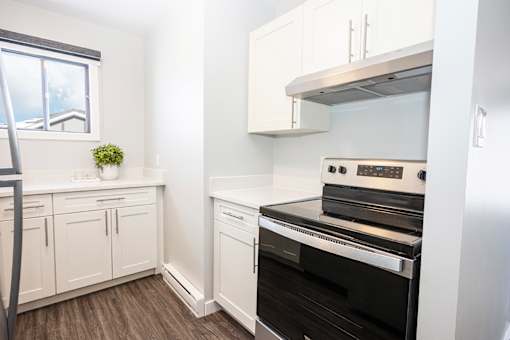 a kitchen with white cabinets and a stove and a window