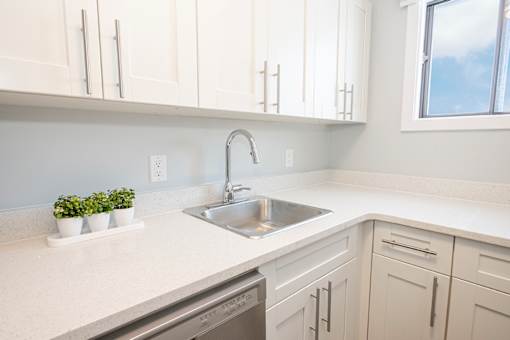 a kitchen with white cabinets and a sink and a window