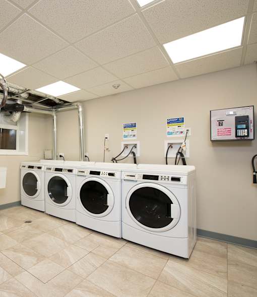 A row of white front load washing machines in a laundromat.