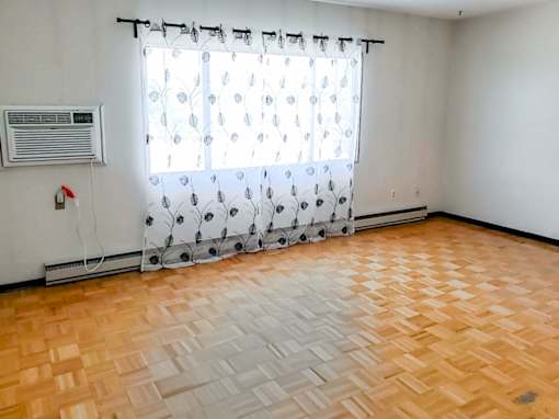 Spacious living room with large windows and natural light at 1025 Munroe Apartments.