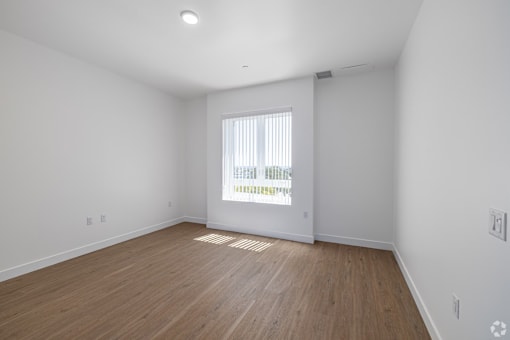 A room with wooden floors and a window with blinds.