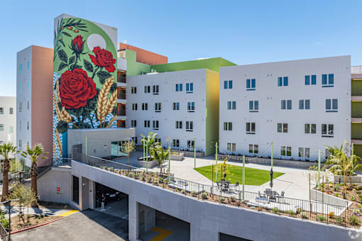 A mural of a red rose is painted on the side of a white building.