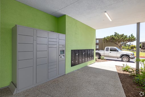 A parking garage with a green wall and a grey truck in the background.