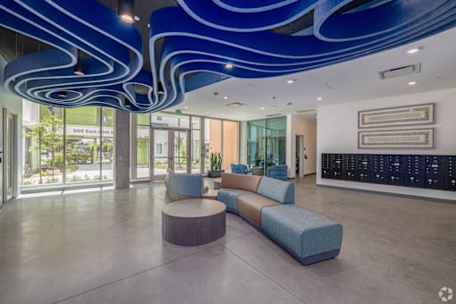 A modern interior with a blue ceiling light fixture and a long blue sofa.