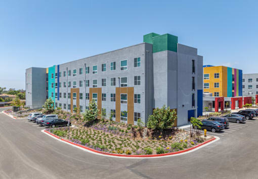 A modern multi-story building with a parking lot in front.