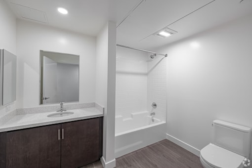 A bathroom with a sink, mirror, toilet, and bathtub.
