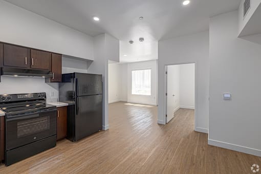 A kitchen with black appliances and wooden floors.