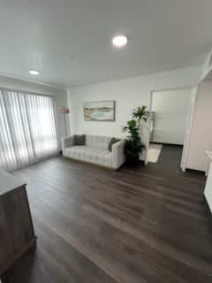 A living room with a white couch and a wooden floor.
