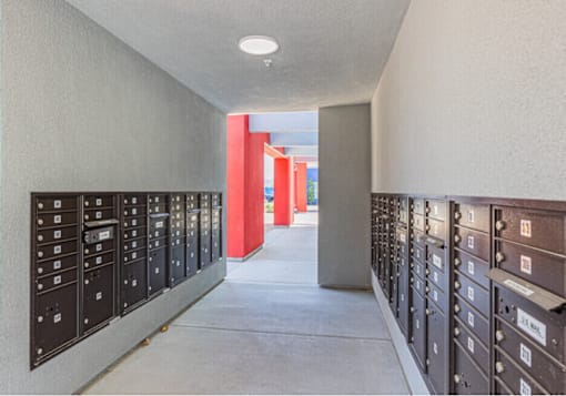 A long hallway with mailboxes on either side and a red column in the middle.
