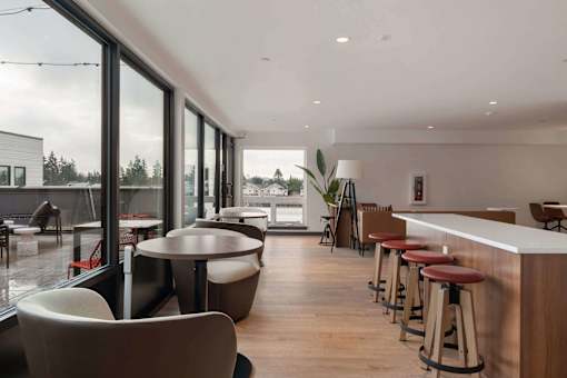 2-Bedroom Apartments in White Center, WA - Elevation16 - Resident Lounge With Plenty Of Seating, A Bar Table, And Large Windows Overseeing The Outdoor Courtyard