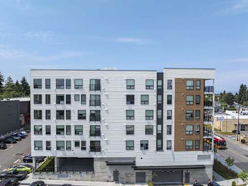 A modern multi-story building with a mix of white and wood paneling.