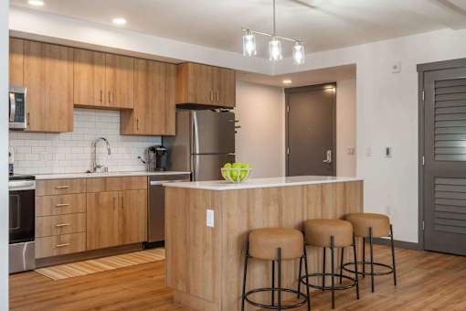 A kitchen with wooden cabinets and a counter with three stools at Elevation16 Apartments, Washington